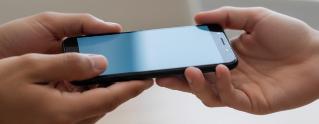 Ein Smartphone wird von einer Person an eine andere übergeben.